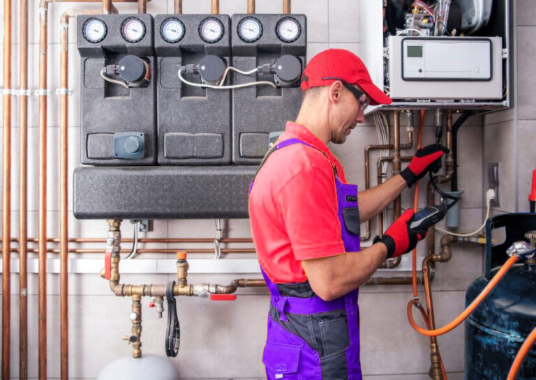 Technicien en rouge et violet inspectant une chaudière avec un appareil de mesure.